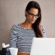 Woman wearing glasses working on a laptop.