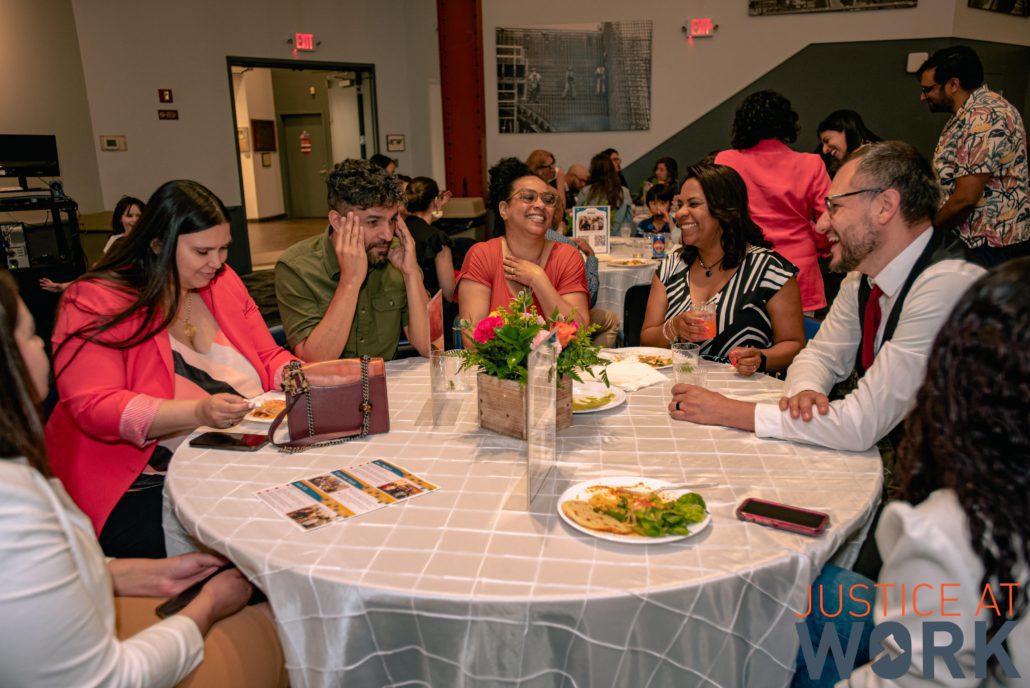 Group laughing around a table at event.